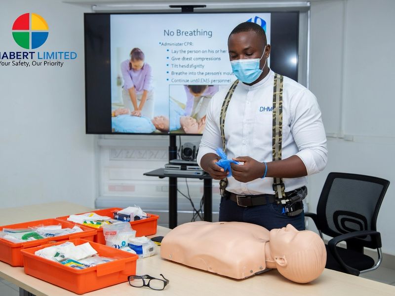 A trainer demonstrating first aid with a CPR manikin and first aid kits